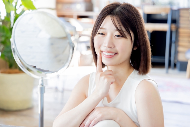 鏡で口元や歯の色を確認する女性